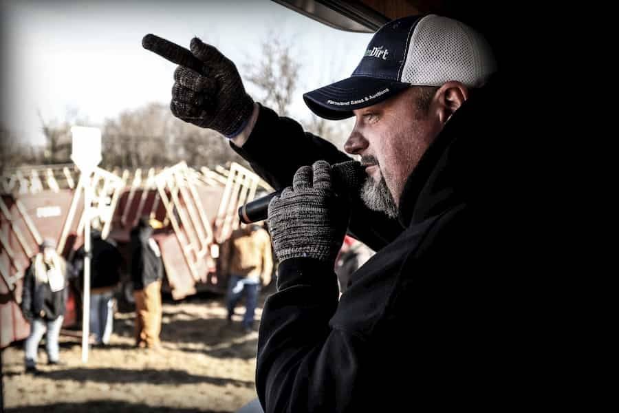 A DreamDirt auctioneer holding a microphone