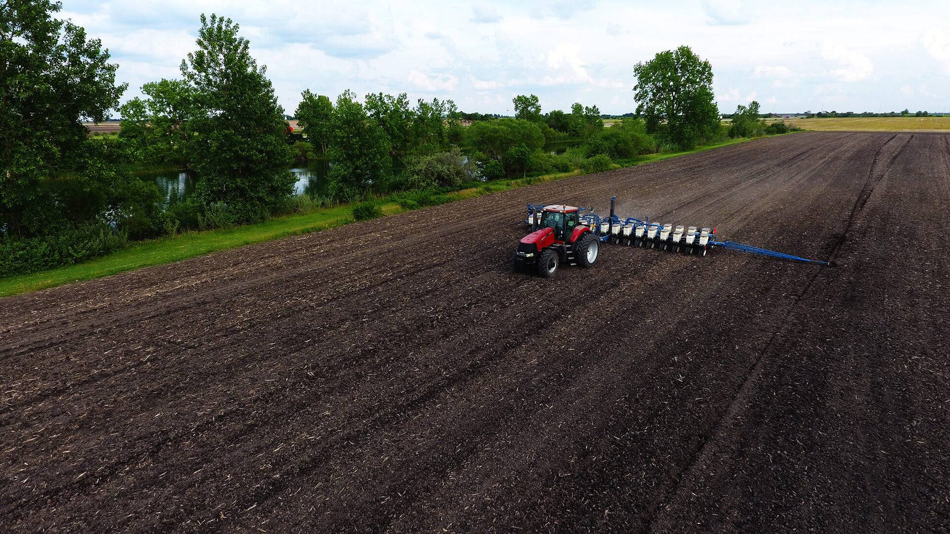 A tractor hauls machinery across a field.