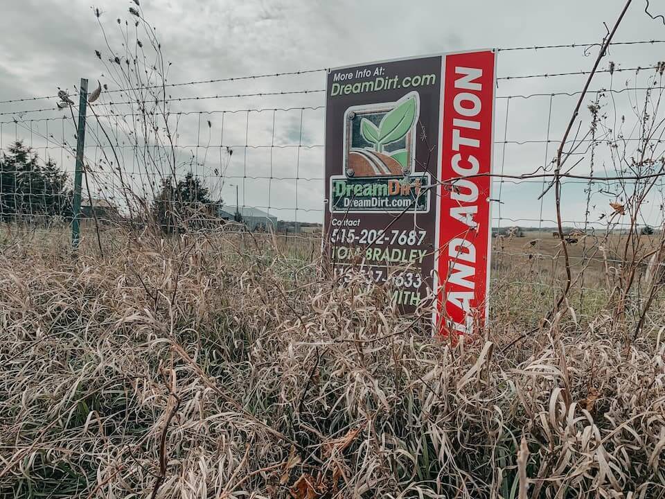 A photo of a land auction sign on a fence.