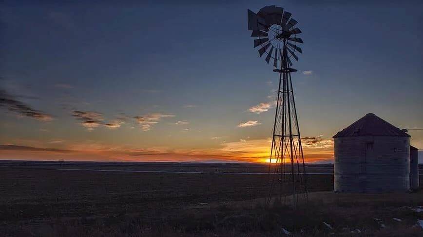 Photo of a windmill with sun setting in the background.