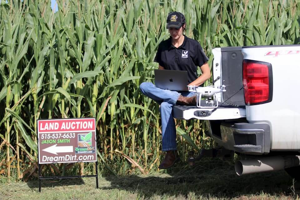 An auctioneer works with a drone at a land auction site.