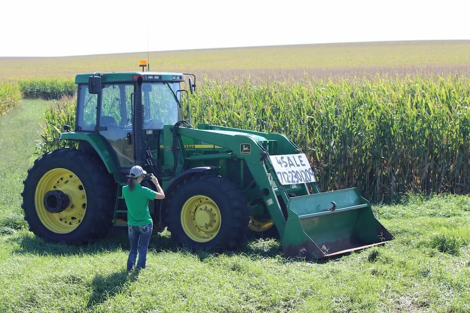 A DreamDirt representative takes pictures of a tractor for sale.