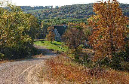 Scenic photo of a gravel road leading to a farm property.